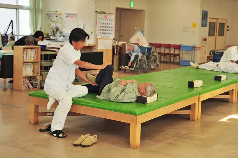 足摺病院のリハビリ室でスタッフが患者さんのリハビリを支援している様子