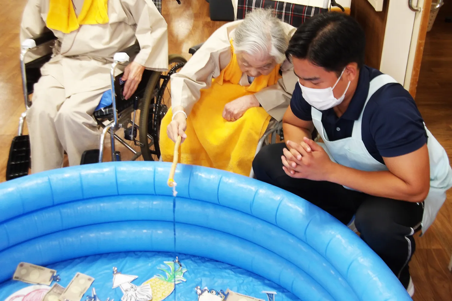 足摺病院の病棟で、患者さんと職員が魚釣りゲームのレクリエーションを一緒に楽しんでいる様子